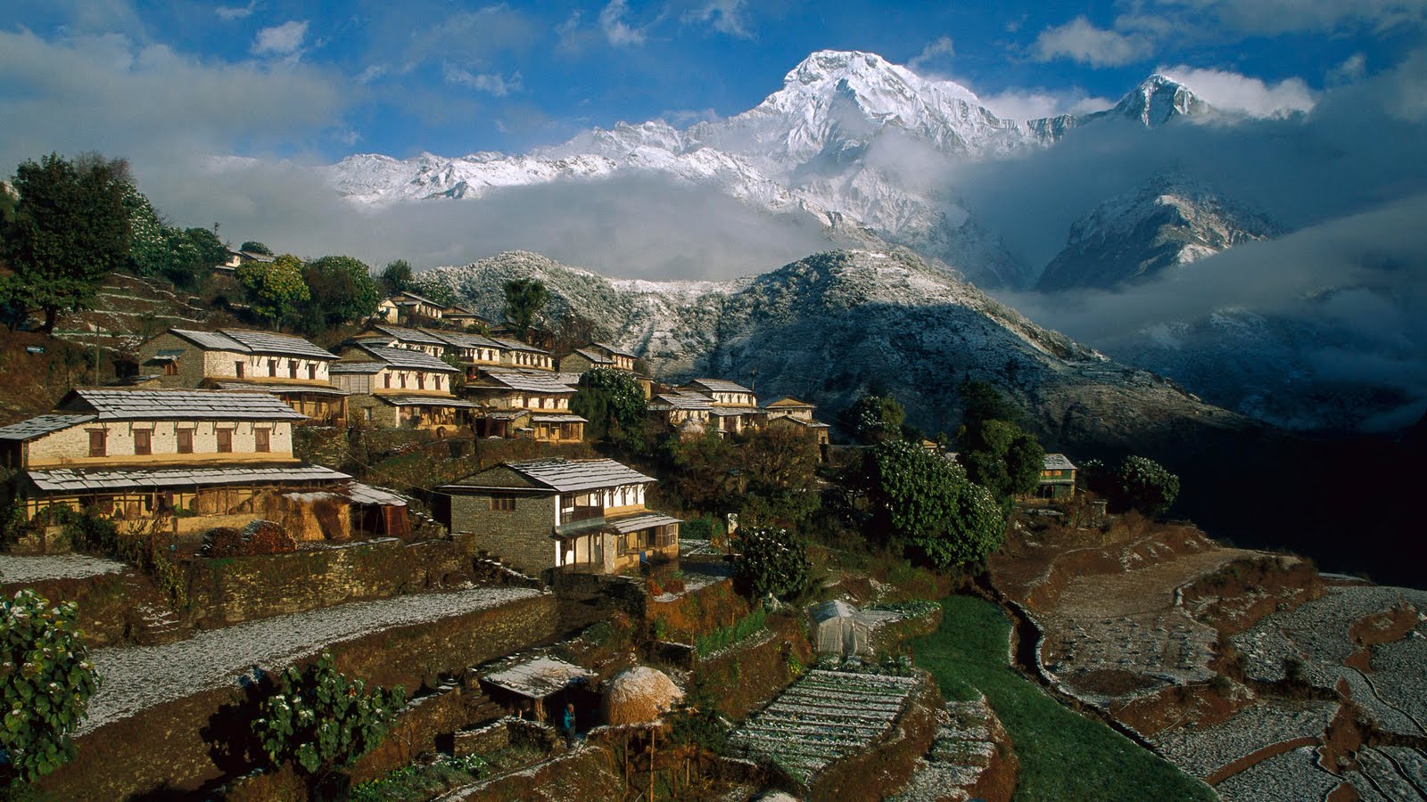 Ghandruk village with a little snow & Annapurna South and Himchuli in the backdrop on a partly cloudy day. 