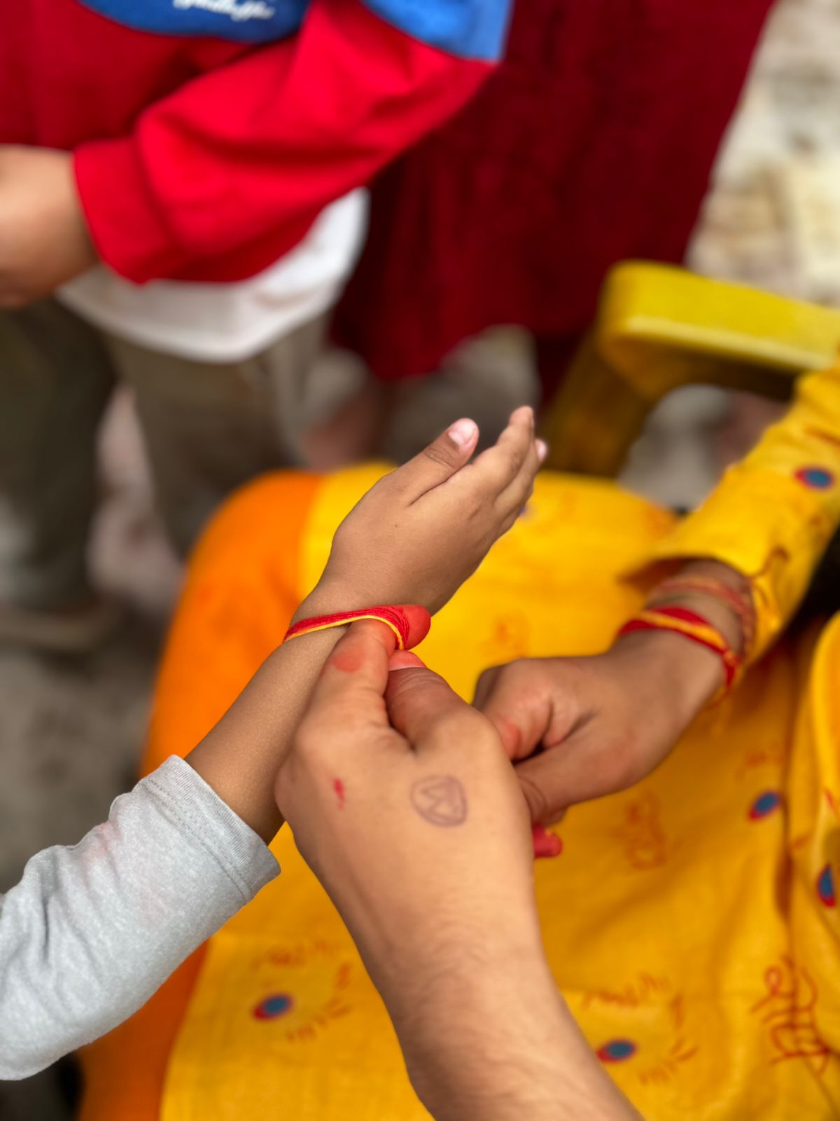 having a sacred thread or bracelet tied around his wrist by another person in a ceremonial setting