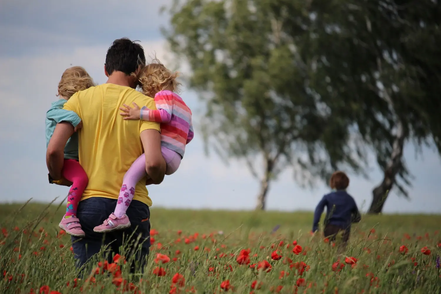 Man carrying two children in a flower garden