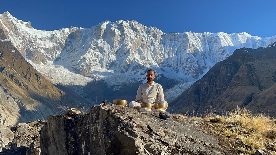 man practicing bowl sound heal therapy Infront of himalayas