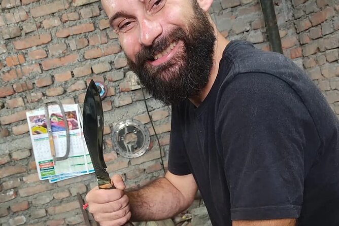 A man with a beard holds a traditional Nepalese Khukuri knife in front of a brick wall, seen through a website's content management system interface on a computer screen