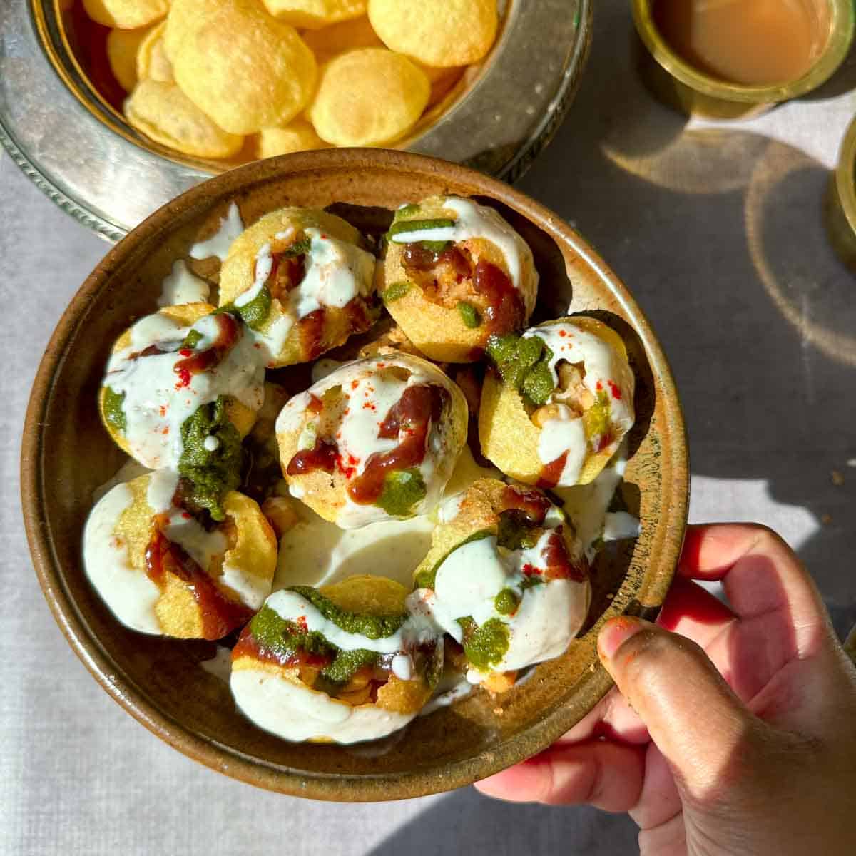 Dahi Puri consists of crispy, hollow puri shells filled with a mixture of boiled potatoes and chickpeas, and then generously topped with sweetened yogurt (dahi), various chutneys (like sweet tamarind chutney and spicy green chutney), and garnished with sev (crispy fried gram flour noodles), and sometimes chopped onions, tomatoes, or pomegranate seeds.