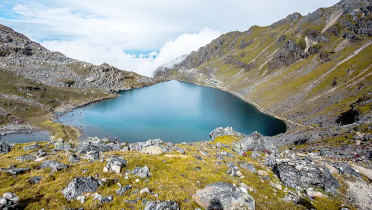high-altitude glacial lake nestled among mountains, strongly resembling scenes found in the Himalayas, particularly in Nepal.